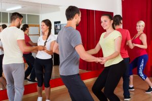 Happy men and women enjoying active dance at a dance studio