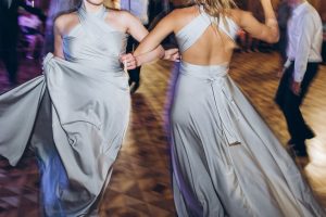 happy stylish bride and bridesmaids dancing and having fun at wedding reception in restaurant. guests dancing in light, people in motion at party in club. fun moments.