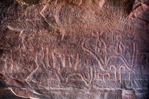 Ancient Nabatean and Thamudic inscriptions on rock representing camel caravan and humans. Khazali canyon, Wadi Rum desert, Jordan