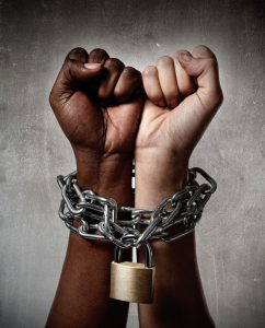 white Caucasian hand chained with iron chain and locked together with black ethnicity female around wrists in togetherness, multiracial respect and understanding concept